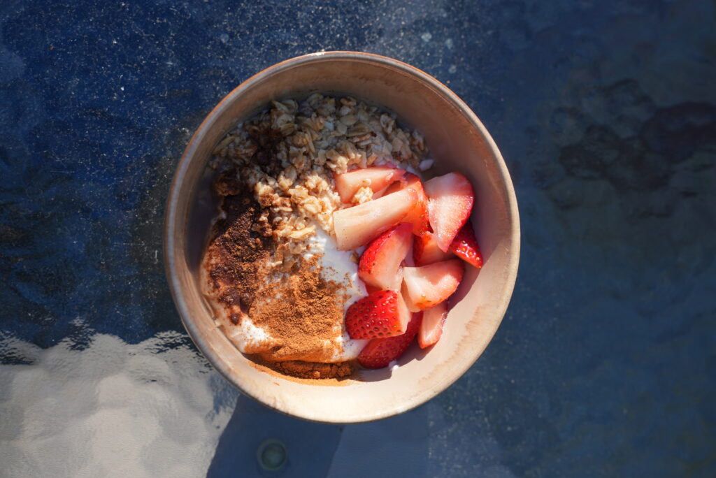 A ceramic breakfast bowl filled with creamy white yogurt, topped with sliced fresh strawberries, a sprinkle of crunchy granola, and a light drizzle of honey, served at a residential treatment center in Agoura Hills.
